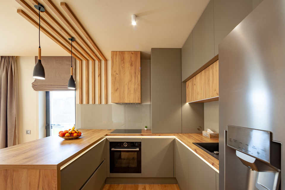 Cocina rectangular con isla americana con muebles cubiertos de madera